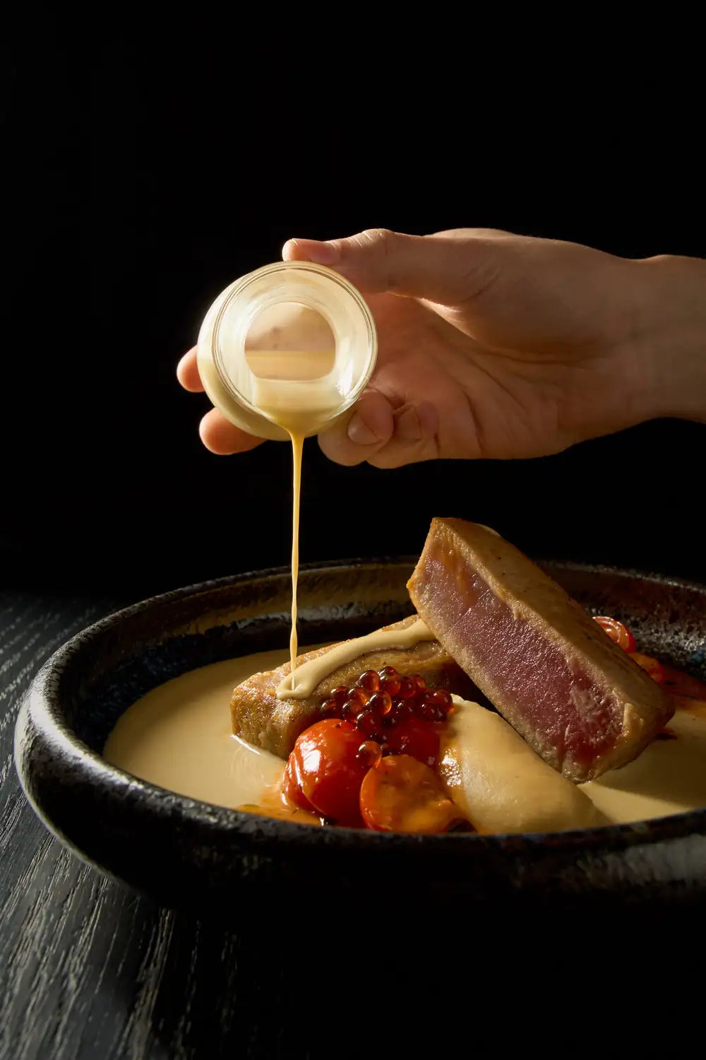 Gebratener Thunfisch mit Sauce und Kirschtomaten auf weißem Teller